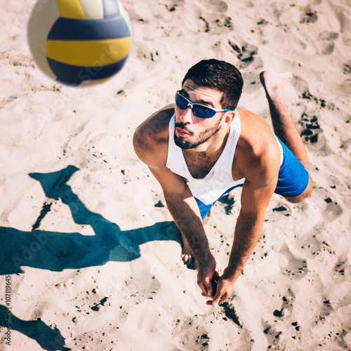 Beach volleyball male player in action, receiving the ball