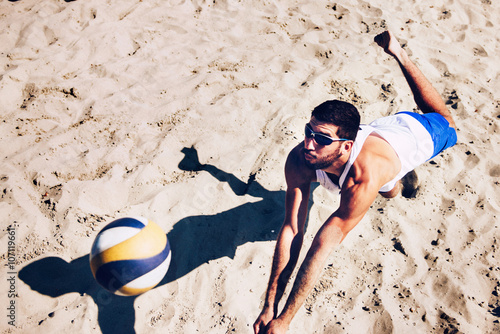 Beach volleyball male player chasing the ball