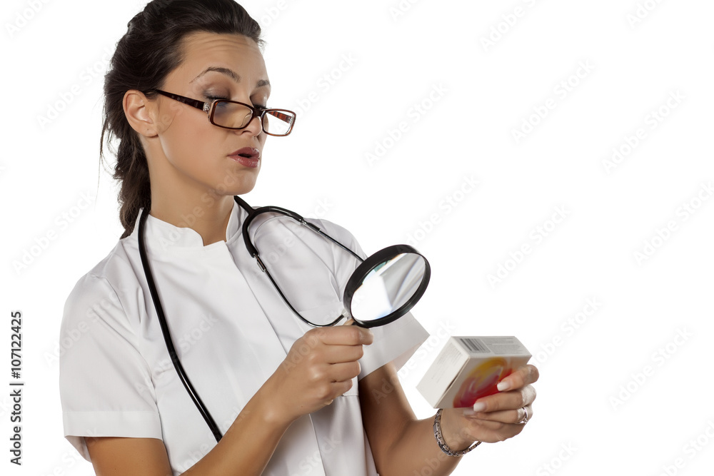 a young woman doctor reading instruction from a box with medicine a young woman doctor reading instruction from a box with medicine