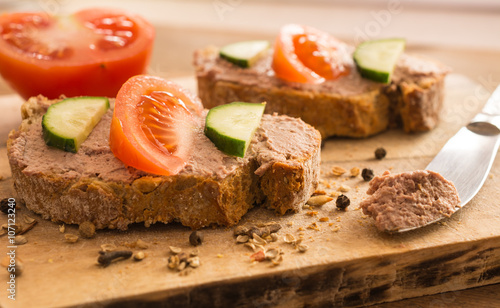 Slices of bread with chicken liver pate on wooden cutting board