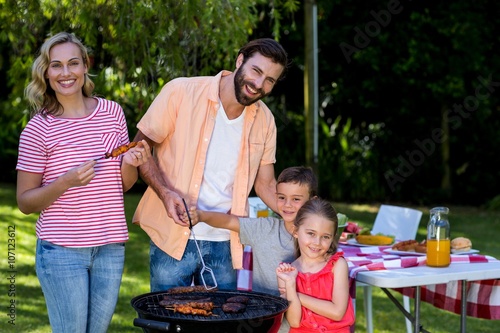 Family cooking food on barbecue grill in yard 