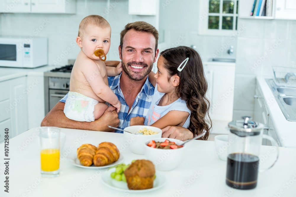 Smiling man with two children having breakfast in kitchen Smiling man with two children having breakfast in kitchen