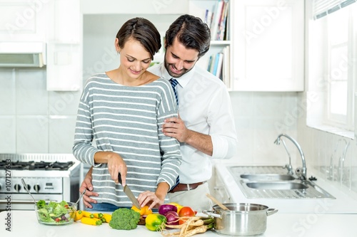 Couple chopping vegetables at table in kitchen 