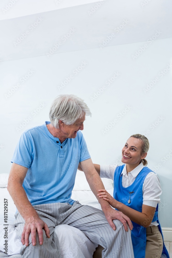 Obraz premium Smiling nurse comforting senior man in hospital