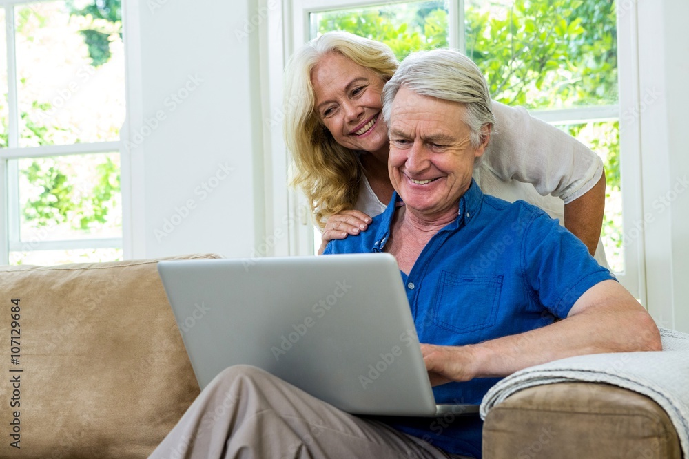 Happy senior couple using laptop while sitting at home Happy senior couple using laptop while sitting at home