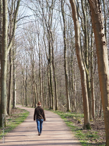 Female walking along at a track in a forest under blue sky, The Hague, Netherlands 2016