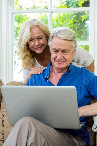 Senior couple using laptop while sitting on at home
