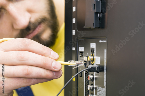 man connects internet cable to the TV
