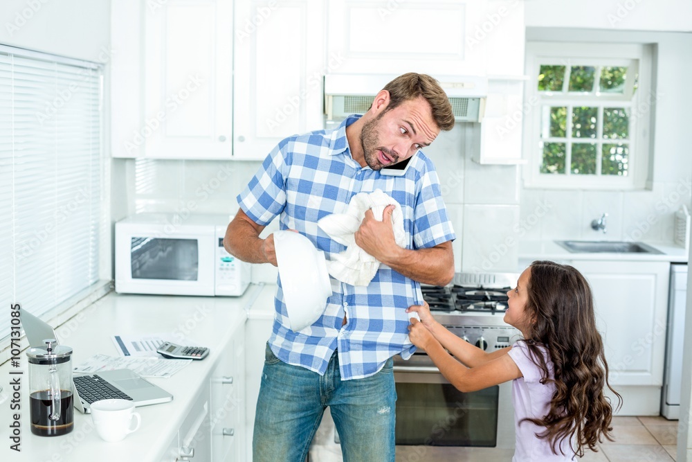 Father wiping container while daughter pulling him Father wiping container while daughter pulling him