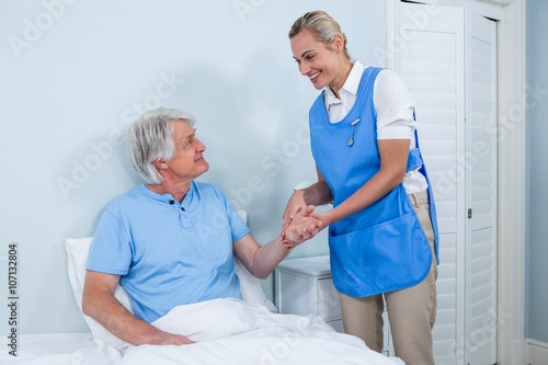 Nurse holding senior man hand in hospital