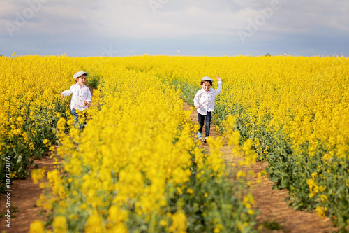 Two adorable children  brothers  running in an oilseed rape fiel