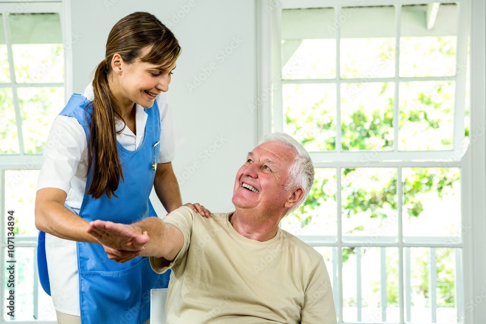 Fototapeta premium Smiling nurse assisting aged man