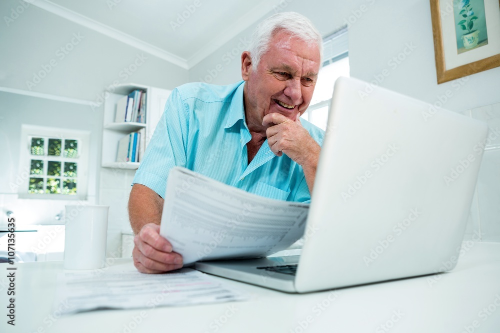 Smiling happy senior man looking into laptop at home Smiling happy senior man looking into laptop at home