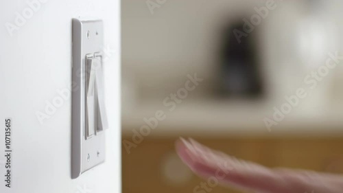 Close up of a hand reaching in and turning light switches on, then off.  Originally recorded in 4K