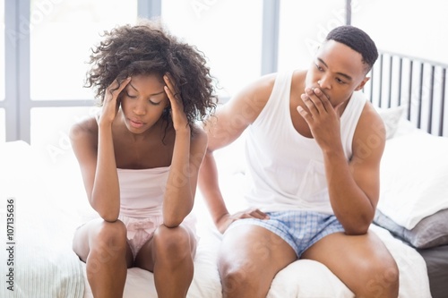 Upset couple ignoring each other after fight on bed photo