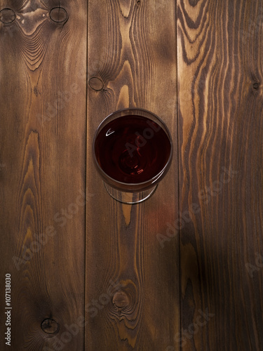 Glass of red wine on the wooden table. Top view