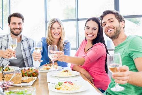 Friends toasting wine glasses while having a meal