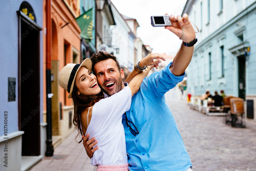 Happy couple taking selfie on the street during vacation in Euro - obrazy, fototapety, plakaty 