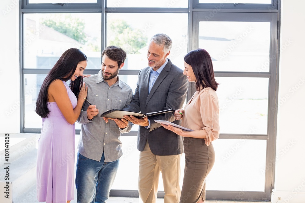 Real estate agent handing over agreement paper to couple Real estate agent handing over agreement paper to couple