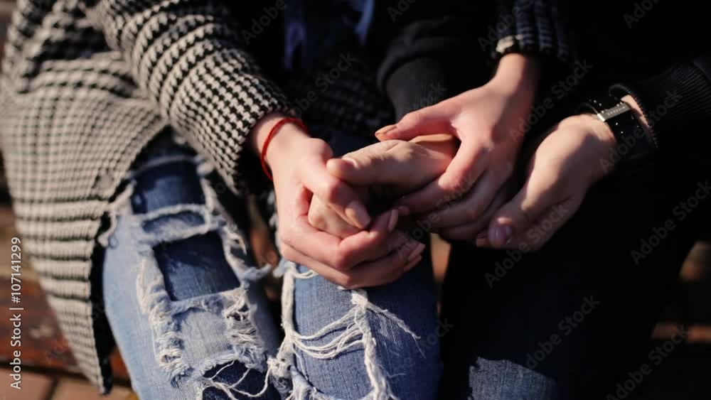 Two lovers holding hands sitting on a bench at the street. Two lovers holding hands sitting on a bench at the street.
