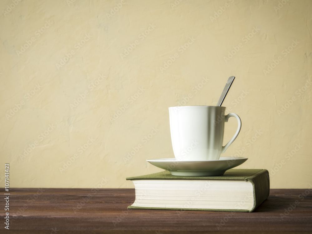 View on the book and cup of tea lying on the wooden table View on the book and cup of tea lying on the wooden table