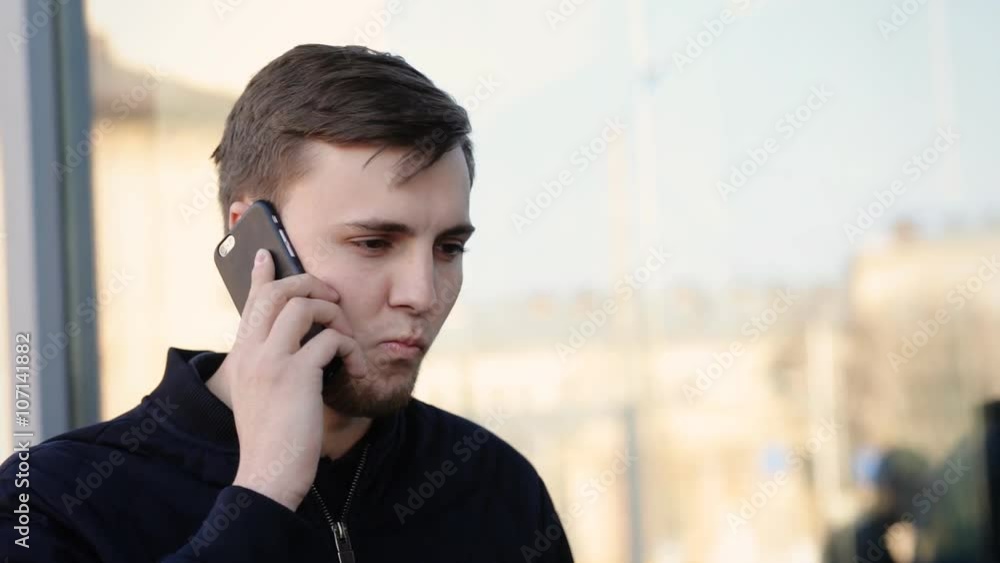 Young handsome man communicating over the telephone in the street. Young handsome man communicating over the telephone in the street.