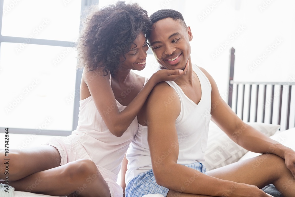 Young couple sitting together on bed Young couple sitting together on bed