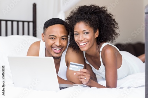Happy couple shopping online through laptop using credit card 