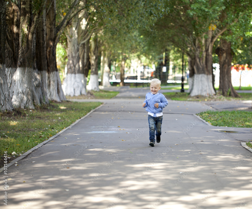 Little boy running on the sidewalk in the summer park Little boy running on the sidewalk in the summer park