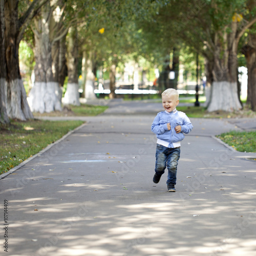 Little boy running on the sidewalk in the summer park © Andrey_Arkusha