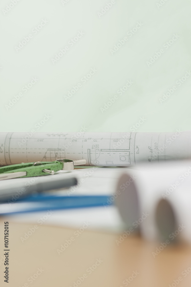 Architectural blueprints and blueprint rolls and a drawing instruments on architects desk