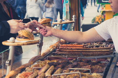 Photography person buying grilled suasage at a fair