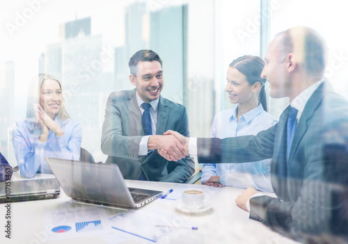 two businessman shaking hands in office photo