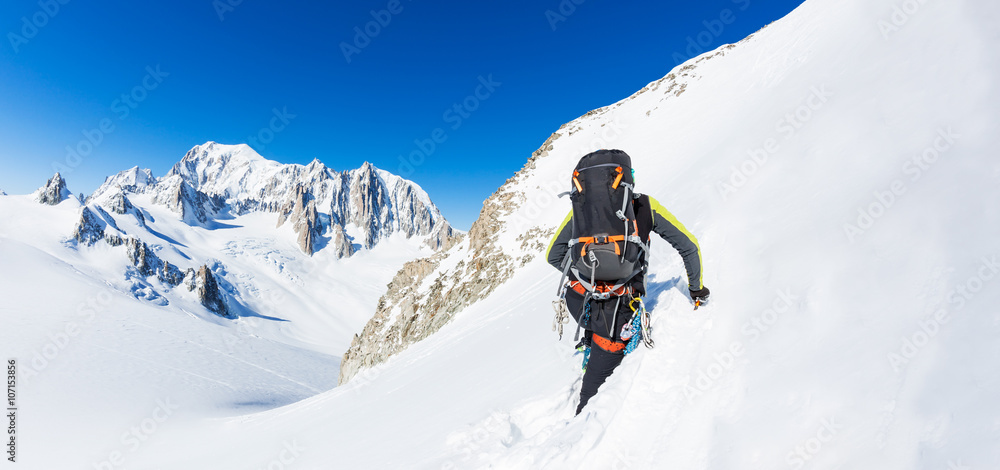 Mountaineer climbs a snowy peak. In background the glaciers and the summit of Mont Blanc, the highest european mountain. The Alps, Chamonix, France, Europe.
