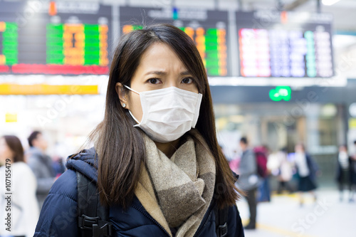 Woman wearing face mask at train station © leungchopan