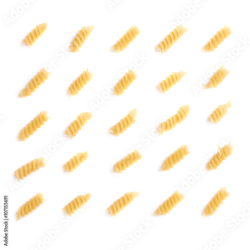 Single pieces of dry rotini pasta over isolated white background
