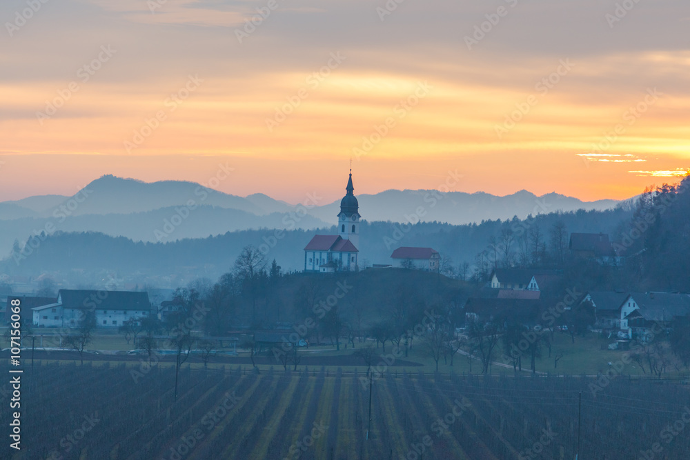 Kamnik, Slovenia - January 25, 2016. Podgorje village, a suburb of the town Kamnik, and Saint Nicholas church at sunset.