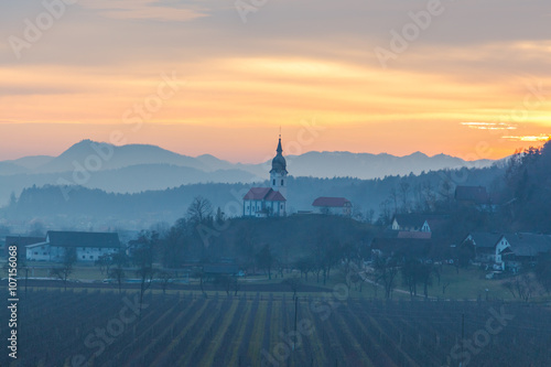 Kamnik, Slovenia - January 25, 2016. Podgorje village, a suburb of the town Kamnik, and Saint Nicholas church at sunset. © donaldyan1