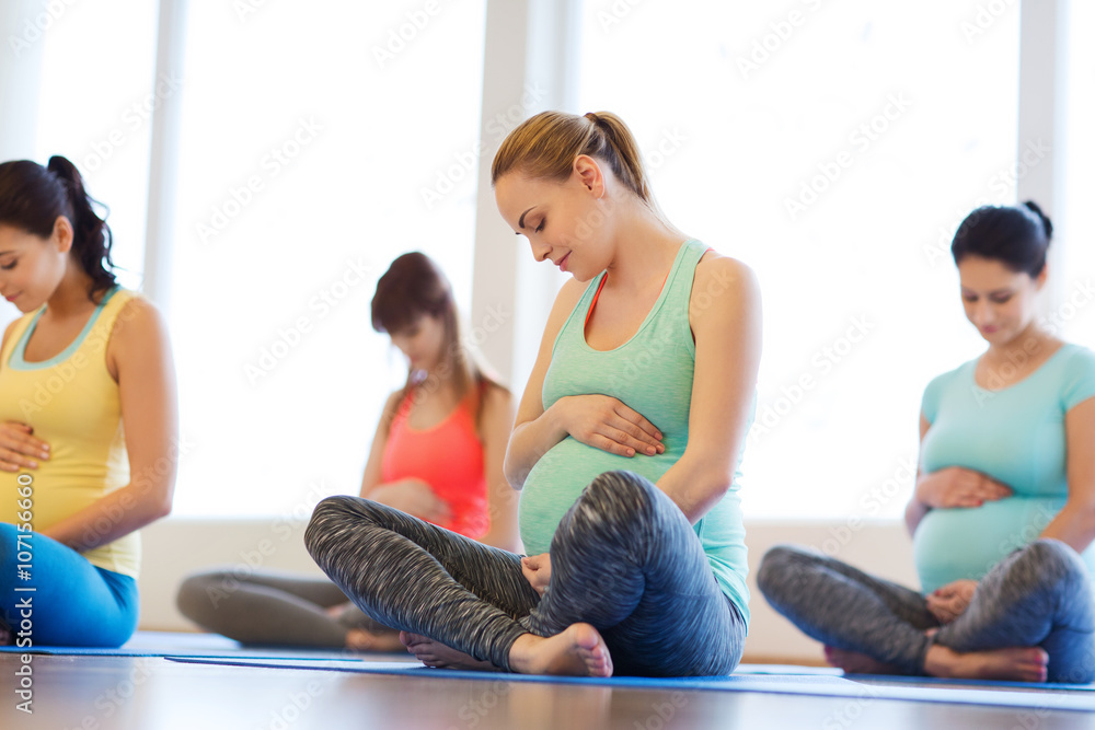 happy pregnant women exercising yoga in gym happy pregnant women exercising yoga in gym