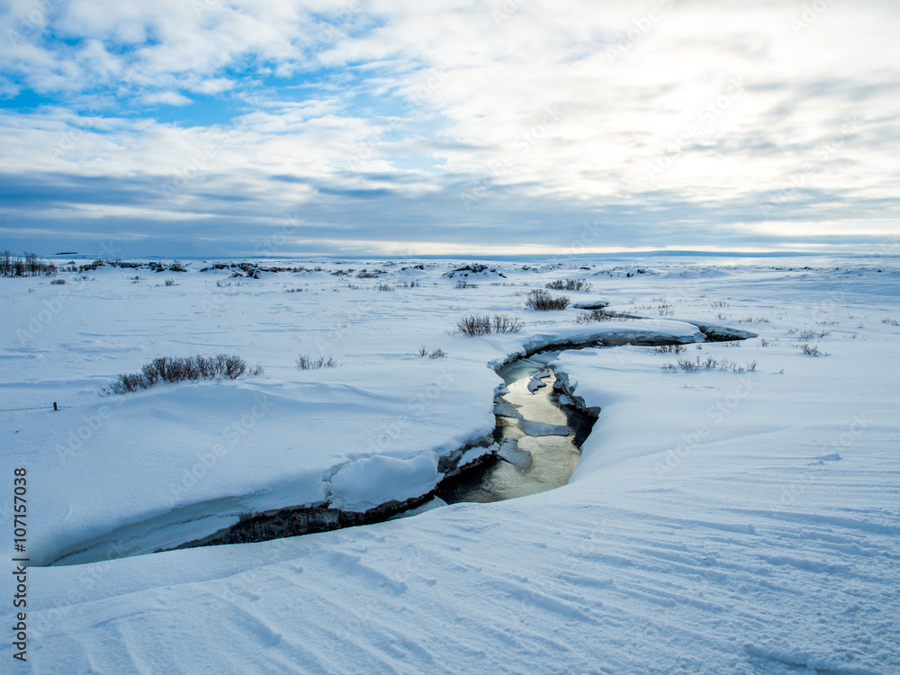 Small river in the middle of snow during winter in iceland