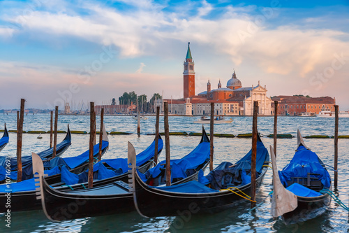 Gondolas moored by Saint Mark square with San Giorgio di Maggiore church in the background in the evening, Venice, Italia