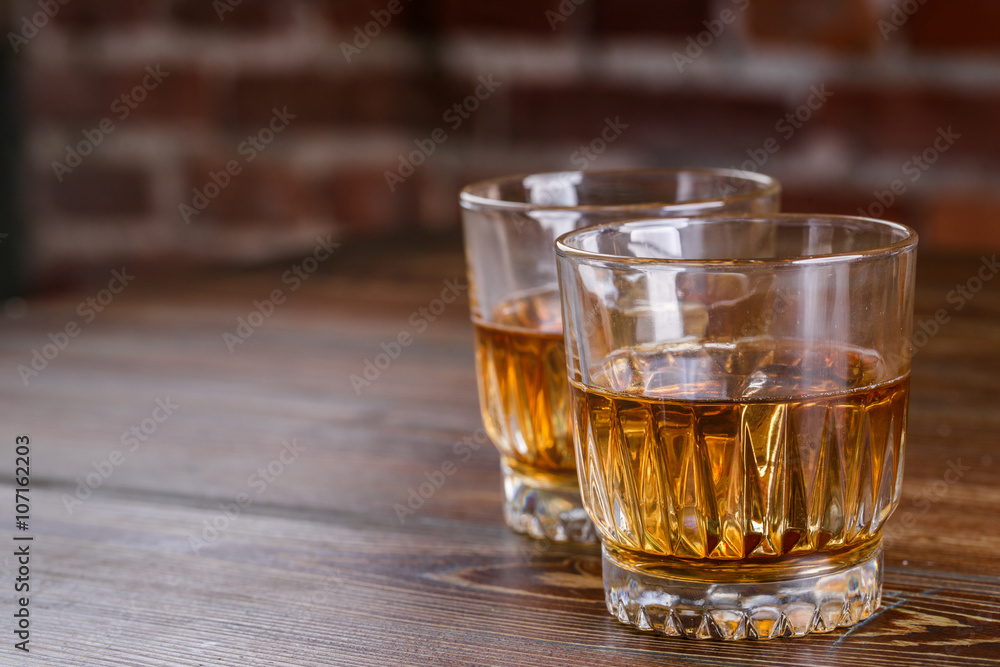 Glasses of whiskey with ice on wood. Glasses of whiskey with ice on wood.
