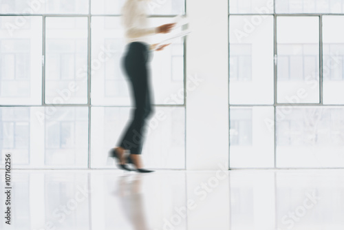 Photo business woman in motion, wearing modern suit. Open space loft office. Holding papers hands. Analyze plans, meeting, panoramic windows background. Motion blur. Horizontal mockup.