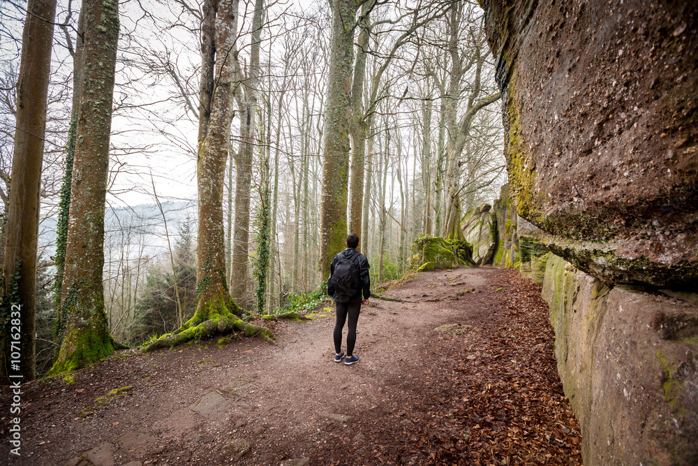 Fototapeta premium Young Man,Student hiking in forest.Man hiker smiling happy portrait on foggy day during a trekking trip. Back of a young man outdoors in nature on a hiker path in forest.