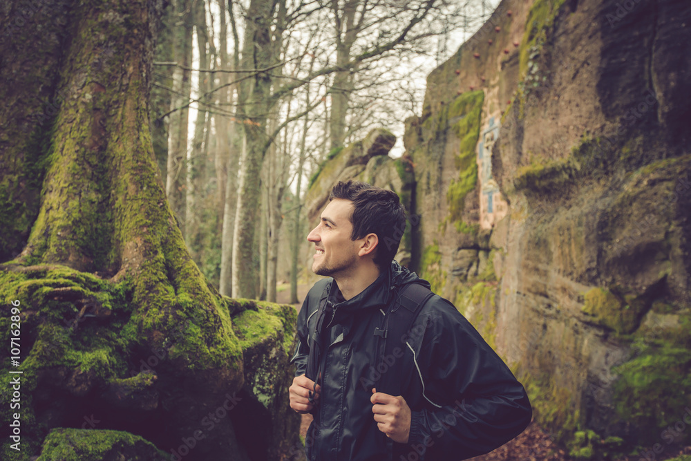 Young Man,Student smiling hiking in forest.Man hiker smiling happy portrait on foggy day during a trekking trip. Back of a young man outdoors in nature on a hiker path in forest.