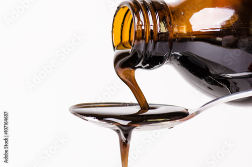 Bottle pouring a liquid on a spoon. Isolated on a white background. Pharmacy and healthy background. Medicine. Cough and cold drug. 