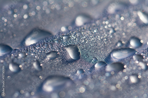 Water droplets on corrugated plastic with refracted light shinning through them at sunrise