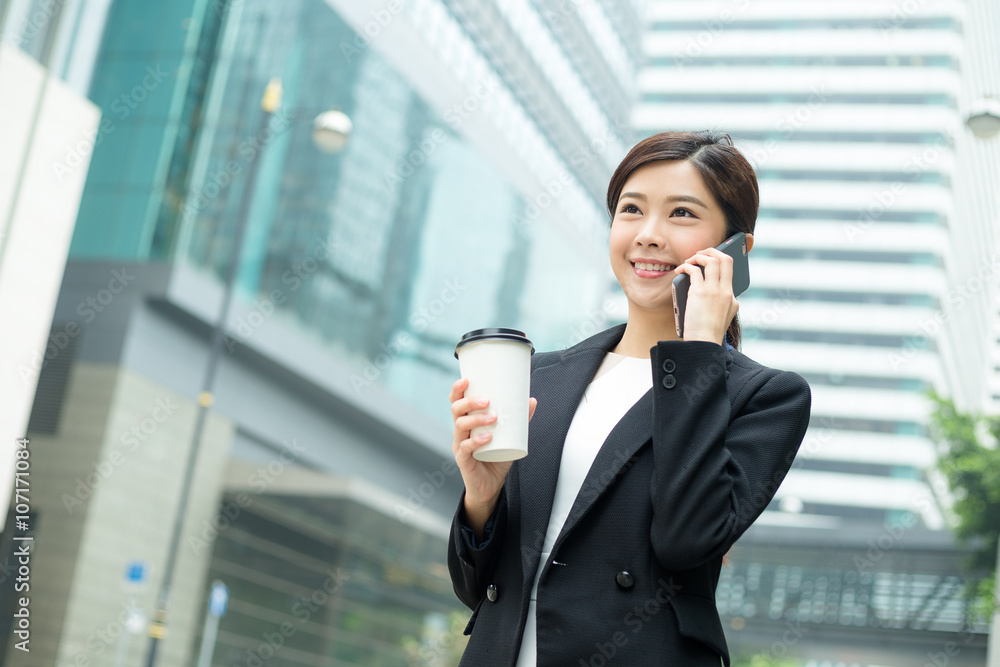 Businesswoman talk to mobile phone and holding coffee cup Businesswoman talk to mobile phone and holding coffee cup