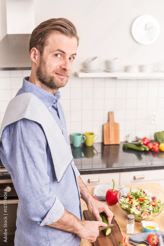 Happy smiling man chopping vegetables to make salad Happy smiling man chopping vegetables to make salad