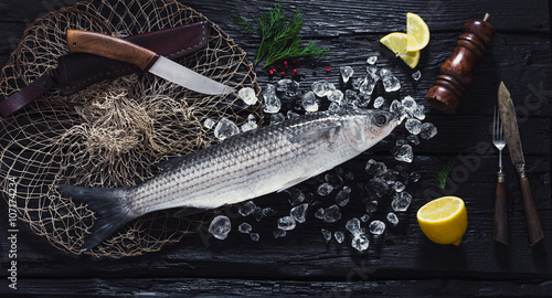 Photography Fresh liza fish on ice on a black wooden table top view